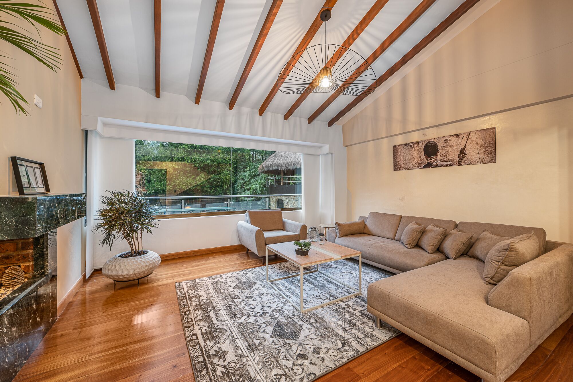 Un salon moderne avec une grande fenêtre, un canapé, une table basse et une cheminée.