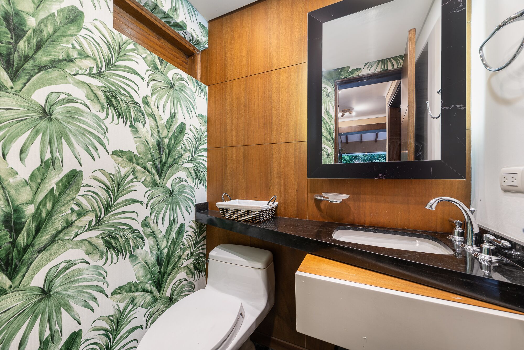 A bathroom with a toilet, sink, and mirror.