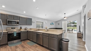 A modern kitchen with stainless steel appliances, wooden flooring, and a view to the backyard. - **Luxury 4 bedroom Villa w/ pool in golf community, mins away from DisneyWorld** (Davenport)