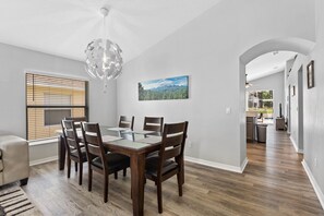 A dining area with a wooden table and chairs, a chandelier, and a window with blinds. - **Luxury 4 bedroom Villa w/ pool in golf community, mins away from DisneyWorld** (Davenport)