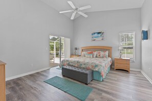 A bedroom with a bed, a bench, a ceiling fan, a window, and a door leading to a balcony. - **Luxury 4 bedroom Villa w/ pool in golf community, mins away from DisneyWorld** (Davenport)