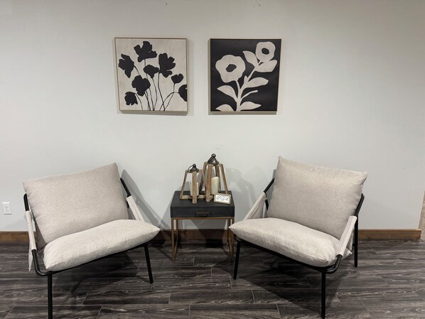 Two armchairs facing each other with a small table between them, featuring a candle holder and a sign.