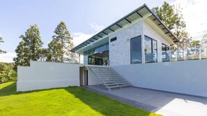 Een modern huis met een witte gevel, grote ramen en een trap naar een overdekte veranda.