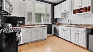 Une cuisine moderne avec des meubles blancs, une cuisinière et un lave-vaisselle.