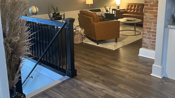 Un salon moderne avec un canapé en cuir marron, une table basse ronde et une cheminée. Un escalier avec une rampe mène à un autre niveau.