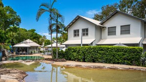A residential area with a swimming pool, white houses, and lush greenery. - 3 Brm Waterfront Apartment (Noosa)