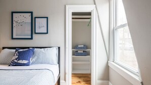 Un dormitorio con cama, armario y ventana.