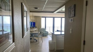 Een hotelkamer met balkon, eethoek en uitzicht op zee.