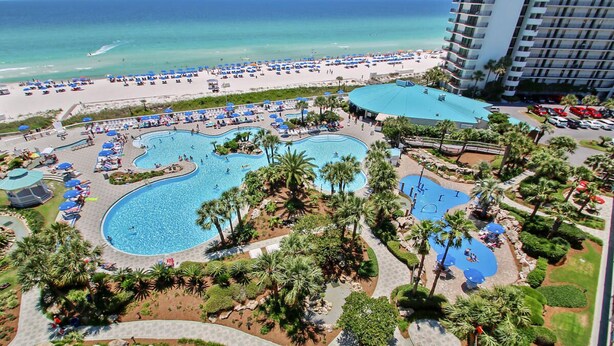 Een resort met meerdere zwembaden, een strand en een groot hotelgebouw.