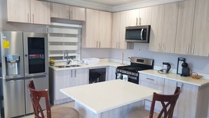 Una cocina moderna con electrodomésticos de acero inoxidable, una isla central y armarios de madera.
