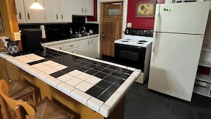 Eine Küche mit Kochinsel, weißen Schränken, einem Herd und einem Kühlschrank.