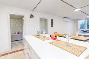 A modern kitchen with a white countertop, a fruit bowl, and two wine glasses. - POOL & SPA - wellness VILLA St Martin, Mġarr, Malta (Mġarr)