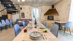 A dining area with a long table set for six, chairs, a sofa, a fireplace, and a staircase. - POOL & SPA - wellness VILLA St Martin, Mġarr, Malta (Mġarr)