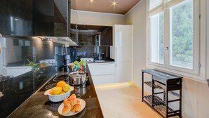 A modern kitchen with a black countertop, white cabinets, and a window with a view of greenery.