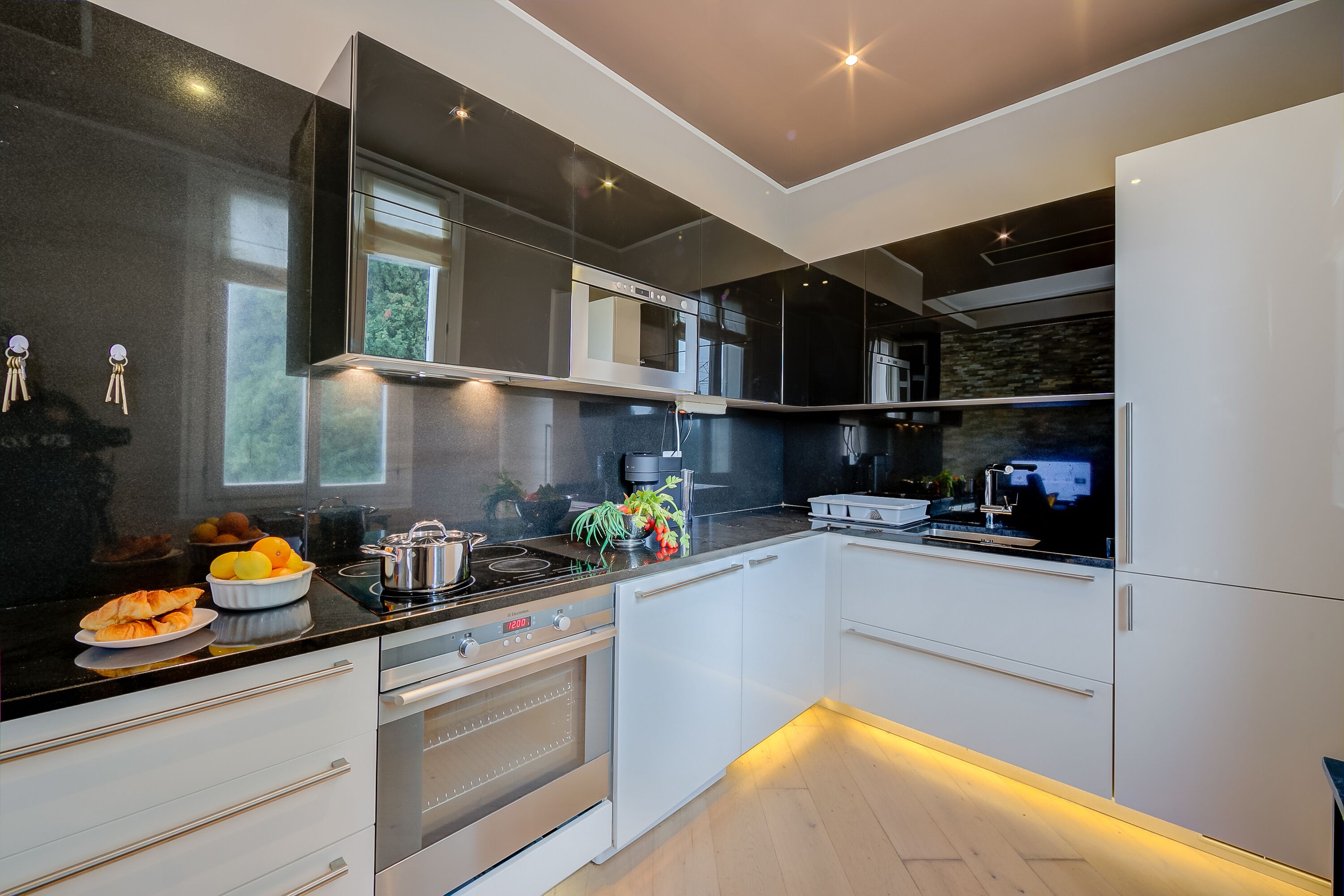 A modern kitchen with white cabinets, a black countertop, and stainless steel appliances.