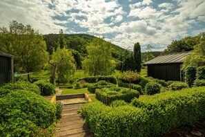 A well-maintained garden with a wooden pathway leading to a bench, surrounded by neatly trimmed hedges and trees. - Apartment 'Happynest' with Mountain View, Private Terrace and Wi-Fi (Birresborn)