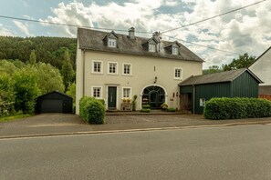 Ein zweistöckiges Haus mit Eingangsbereich, Garage und einem grünen Schuppen.