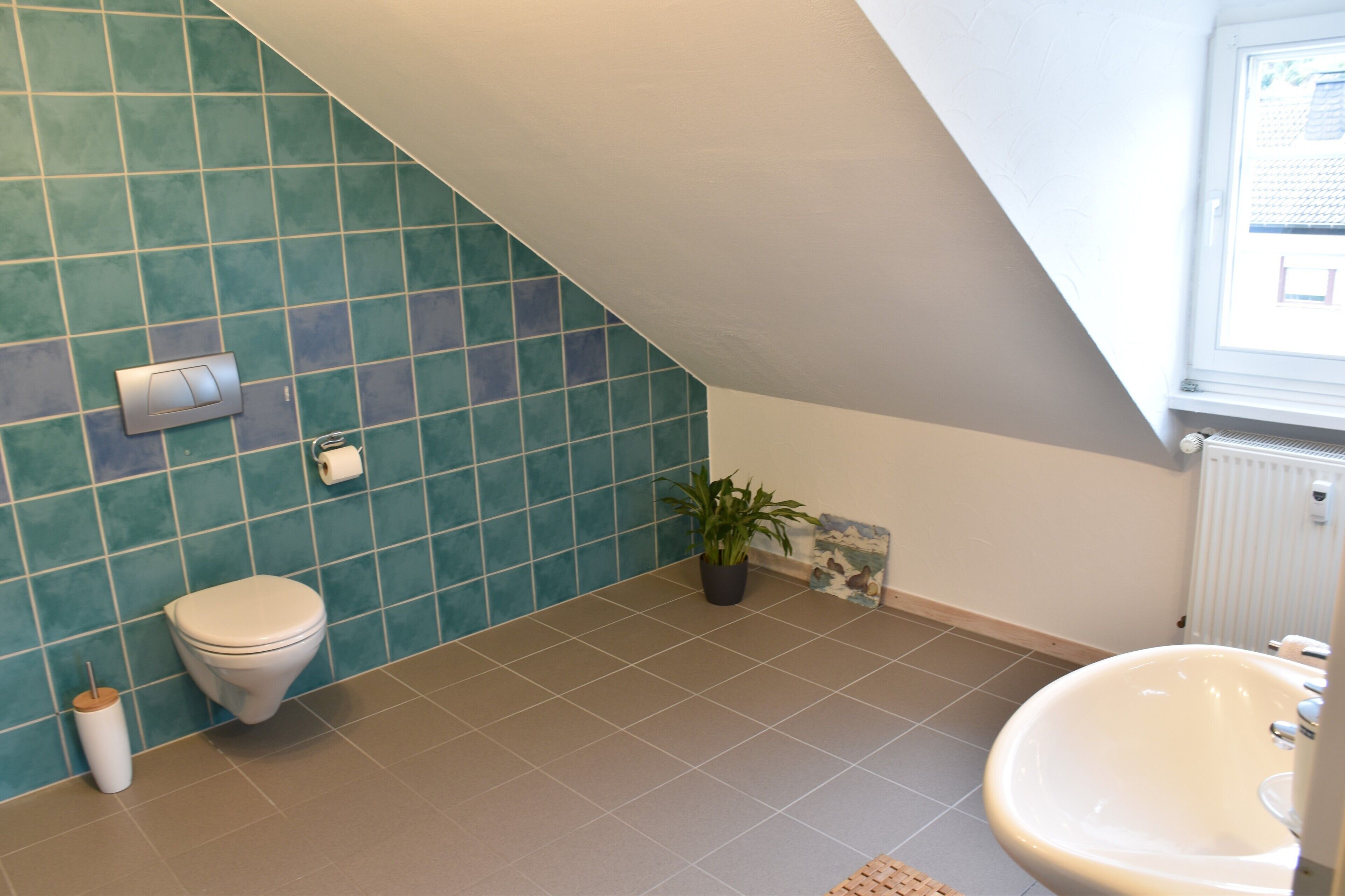 Une salle de bain avec des toilettes, un lavabo et une plante en pot.