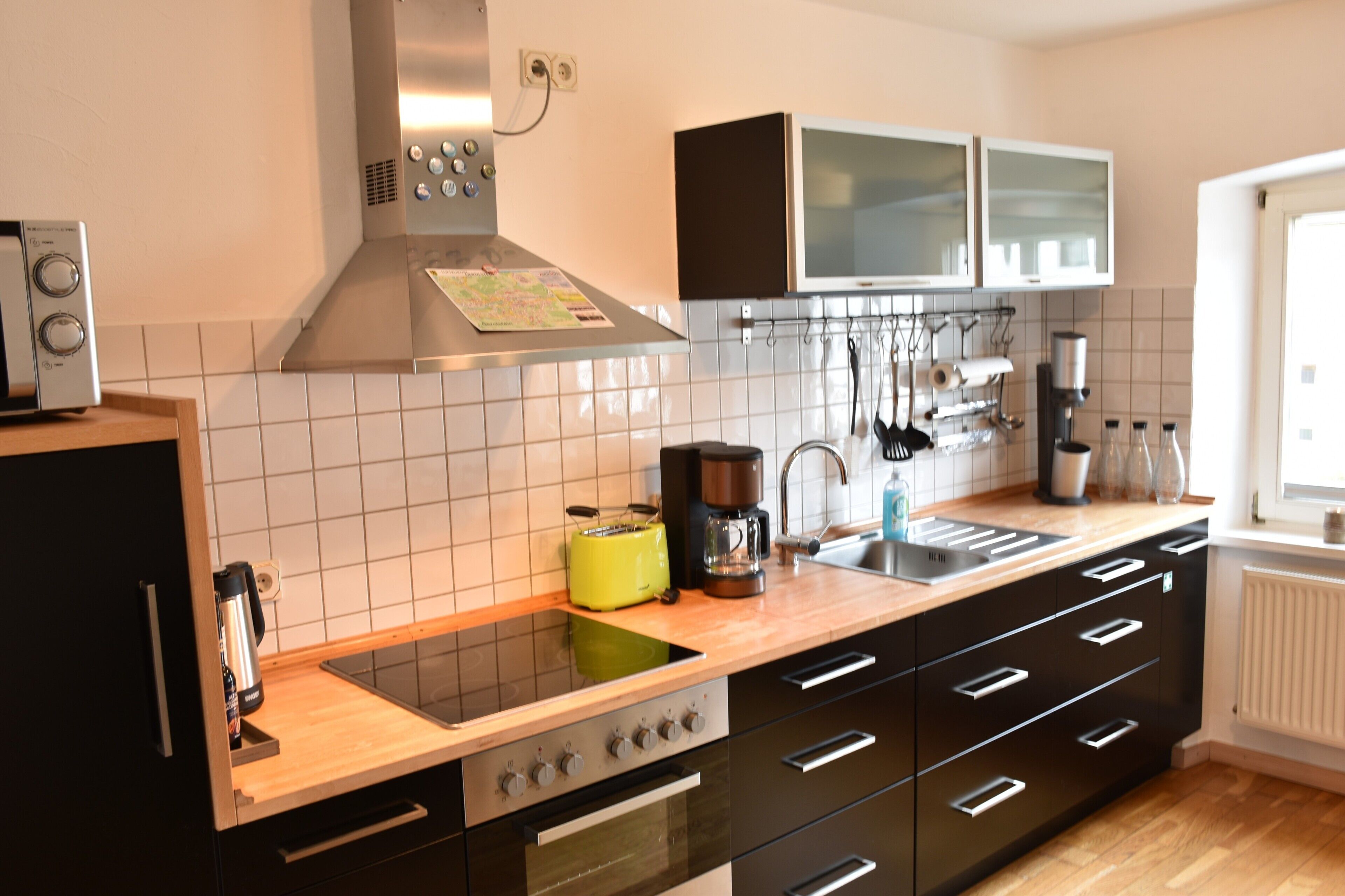 Eine moderne Küche mit Herd, Backofen und Mikrowelle. Es gibt ein Spülbecken mit Armatur sowie eine Arbeitsplatte mit Kaffeemaschine und Toaster.