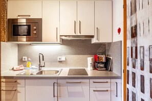 Una cocina moderna con microondas integrado, horno de acero inoxidable y máquina de café.
