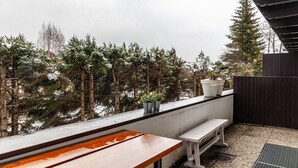 A balcony with a wooden table and bench, potted plants, and a view of snow-covered trees. - Apartment "Haus Excelsior Top 2" with Mountain View, Balcony & Wi-Fi (Seefeld in Tirol)