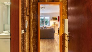 A hallway leading to a living room with a sofa, a window, and a door with a patterned curtain. - Apartment "Haus Excelsior Top 2" with Mountain View, Balcony & Wi-Fi (Seefeld in Tirol)