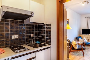 A compact kitchen with a gas stove, sink, and a built-in range hood.