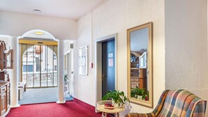 A hotel lobby with a red carpet, a sofa, a mirror, and a door leading to a balcony. - Apartment "Haus Excelsior Top 3" with Mountain View, Balcony & Wi-Fi (Seefeld in Tirol)