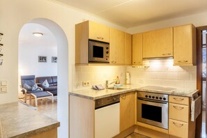 Une cuisine compacte avec des meubles en bois, un four à micro-ondes encastré, une cuisinière et un lave-vaisselle.