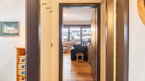 A hallway leading to a living area with a sofa, a small stool, and a wooden cabinet. - Holiday Apartment "Haus Excelsior Top 37b" with Mountain View, Balcony & Wi-Fi (Seefeld in Tirol)