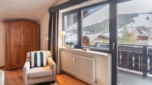 A room with a large window, a radiator, a wooden cabinet, and a striped armchair. - Holiday Apartment "Haus Excelsior Top 37b" with Mountain View, Balcony & Wi-Fi (Seefeld in Tirol)