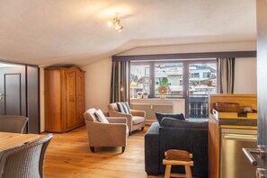 A modern living room with a sofa, chairs, a dining table, and a kitchen area. - Holiday Apartment "Haus Excelsior Top 37b" with Mountain View, Balcony & Wi-Fi (Seefeld in Tirol)