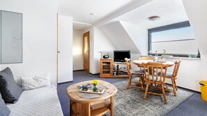 A modern loft-style room with a dining area, a television, and a large window. - Apartment "Whg 2 - Vacation on a Country Estate" with Sea View, Shared Garden, and Wi-Fi (Schönhagen)