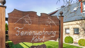 A wooden sign with horse silhouettes and text indicating a horse stable named 'Serienwohnung Kohrt Frei'. - Apartment "Whg 2 - Vacation on a Country Estate" with Sea View, Shared Garden, and Wi-Fi (Schönhagen)