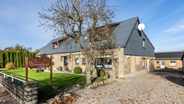 A two-story building with a sloped roof, a satellite dish, and a sign indicating it's a residential property. - Apartment "Whg 2 - Vacation on a Country Estate" with Sea View, Shared Garden, and Wi-Fi (Schönhagen)