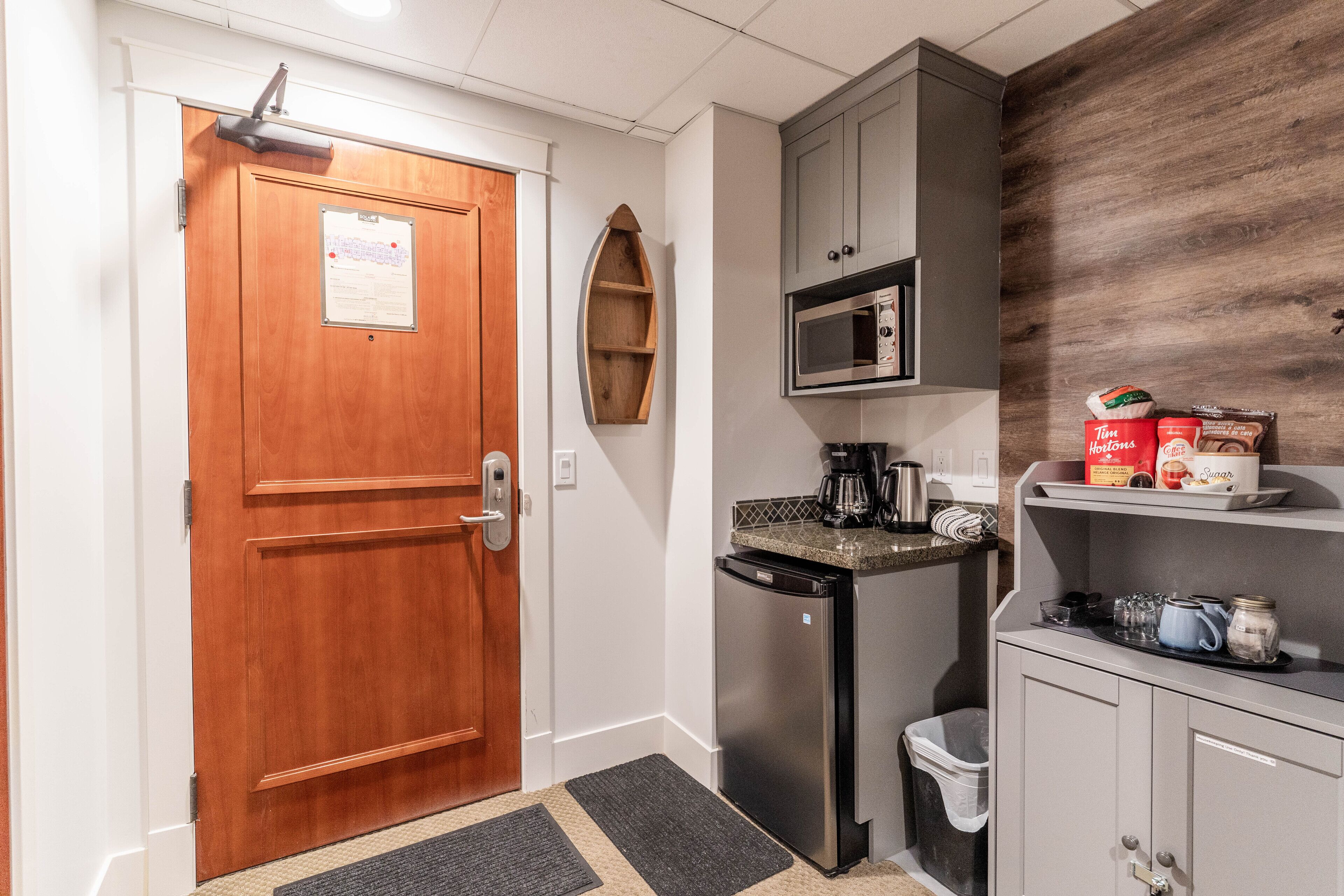A compact kitchenette with a microwave, coffee maker, and a small refrigerator.