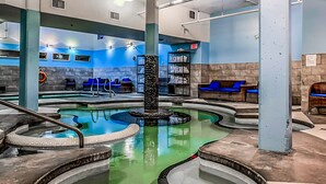 A spa area with a central hot tub, seating areas, and a reception desk. - Luxury Hotel Room Free Parking, Pool &Hot Tub (Canmore)