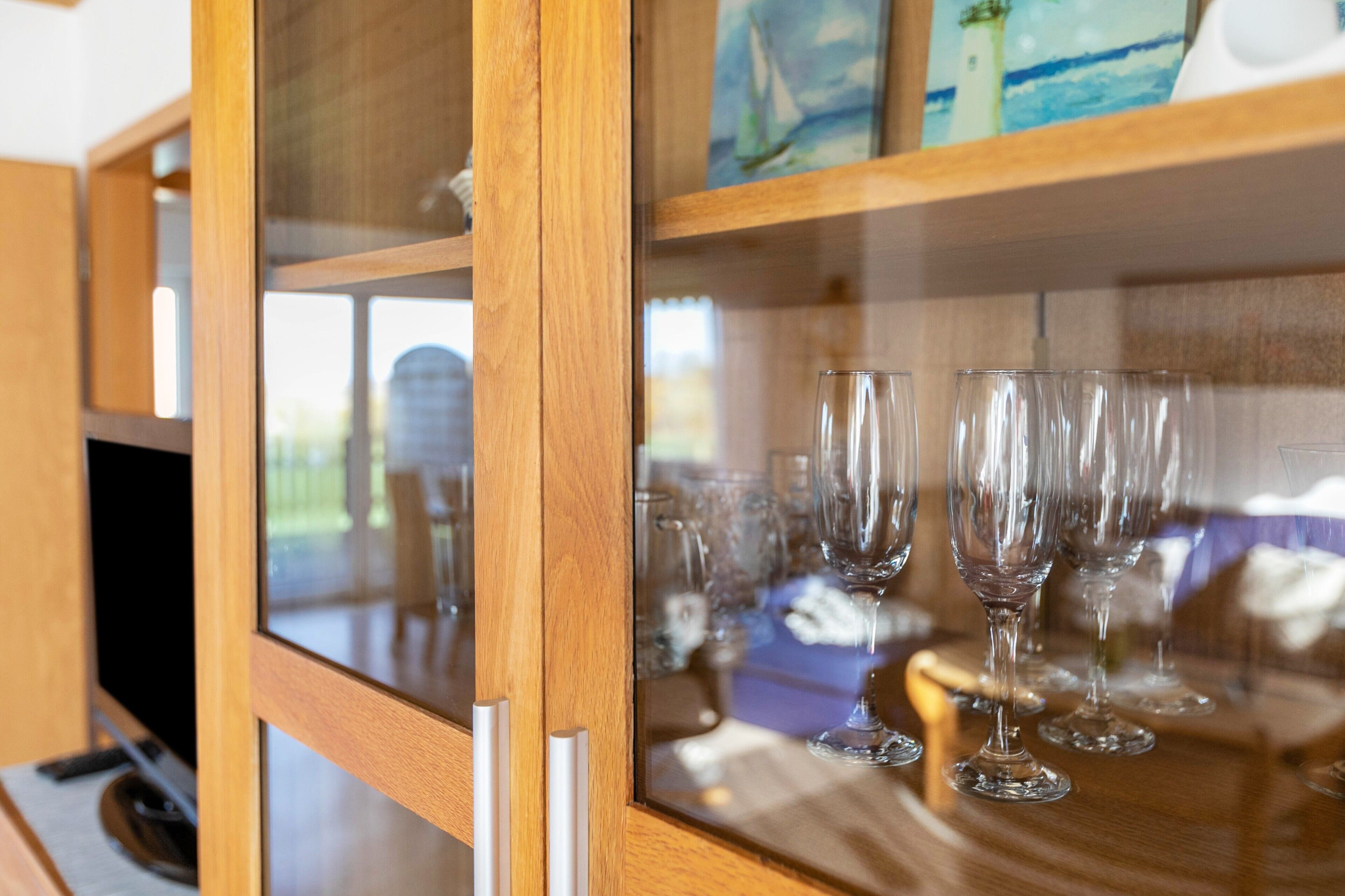 A wooden cabinet with glass doors, containing several clear wine glasses.
