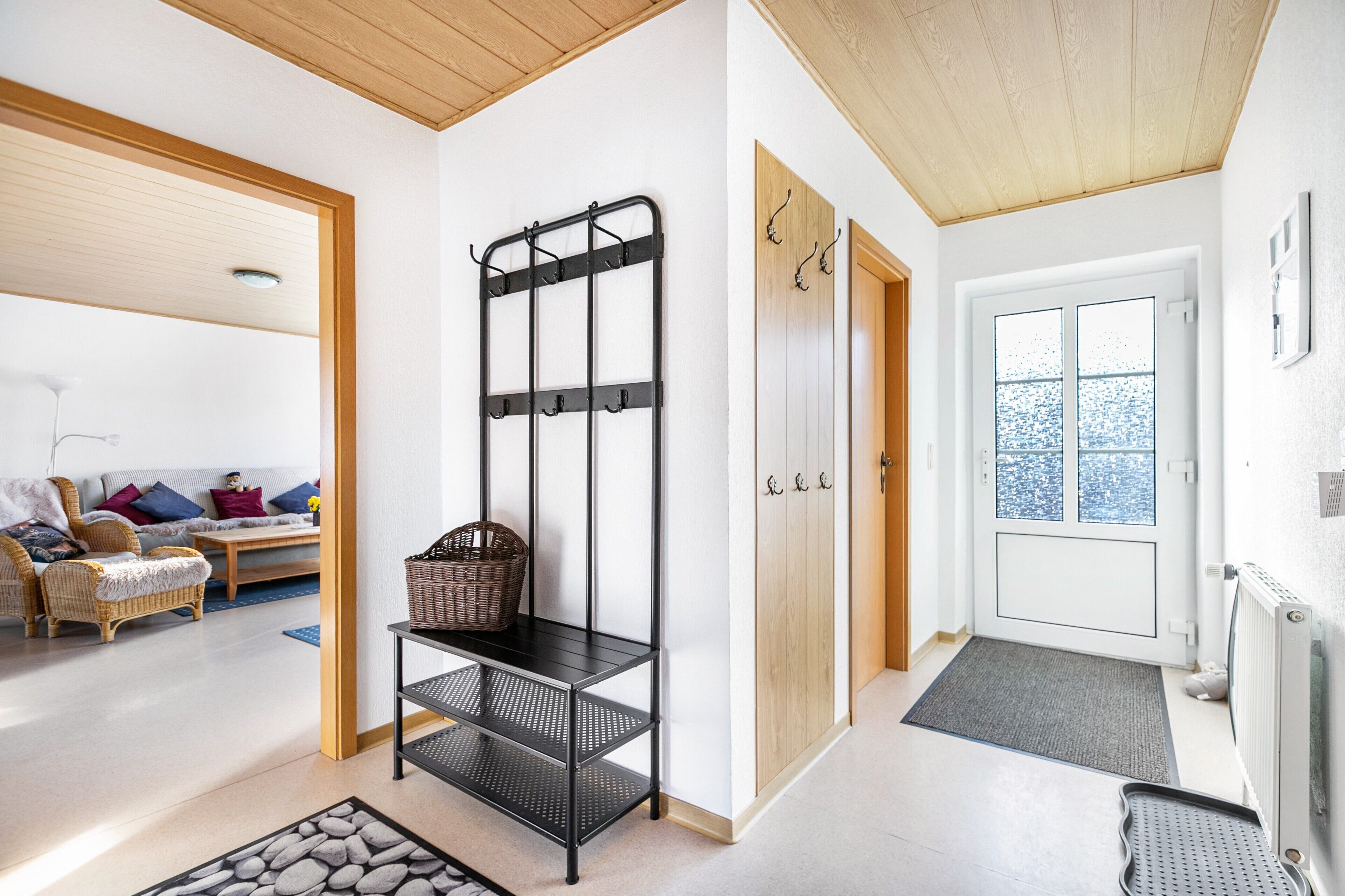 A modern interior with a black metal rack, wicker basket, and a wooden door.
