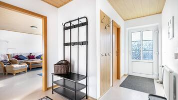 A modern interior with a black metal rack, wicker basket, and a wooden door.
