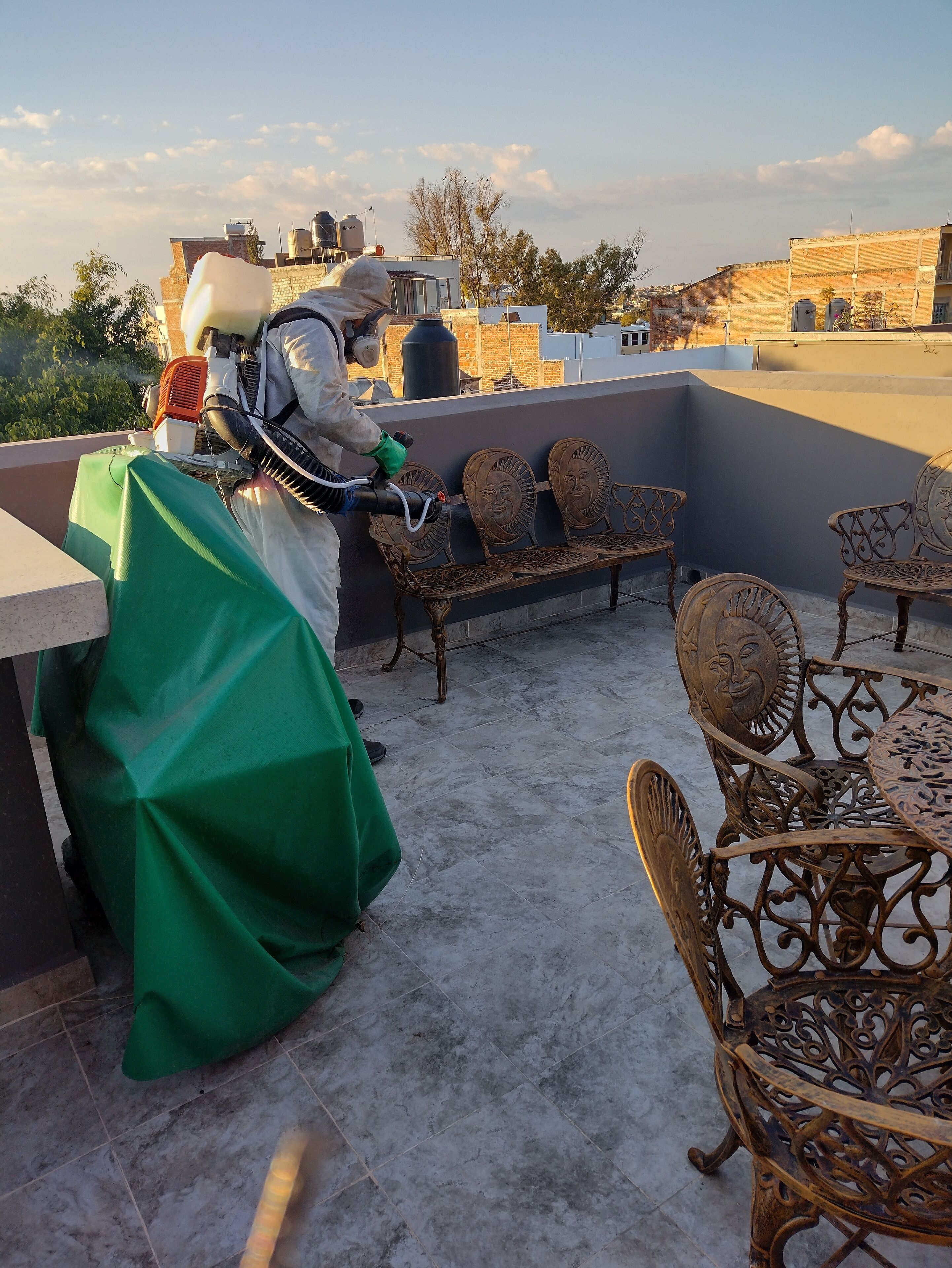 Eine Dachterrasse mit Metallmöbeln, einem Tisch und einem überdachten Bereich.