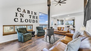 Ein modernes Wohnzimmer mit Kamin, Ledersofas und einem großen Fenster mit Blick auf Bäume.