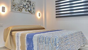 A bedroom with a bed, a wall-mounted artwork, and a window with blinds. - Ceuta apartment near the beach (Conil de la Frontera)