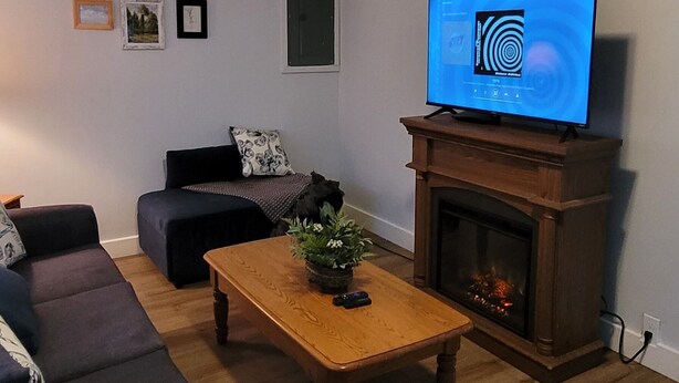 Uma sala de estar com lareira, sofá, mesa de centro e televisão.