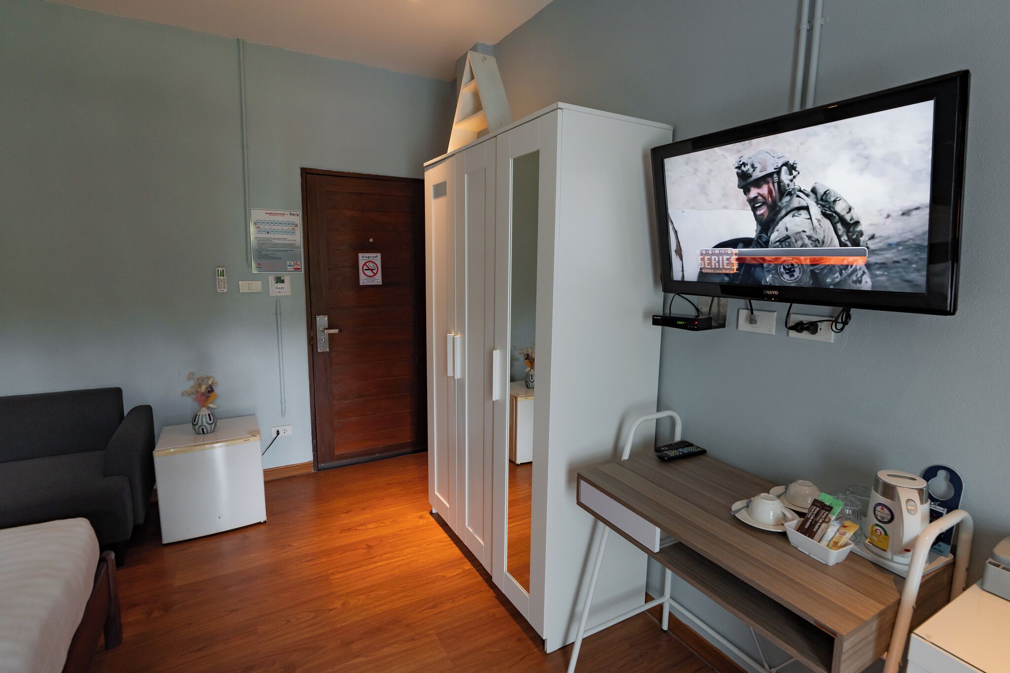 Een hotelkamer met een bed, een bureau met stoel, een televisie en een kledingkast.