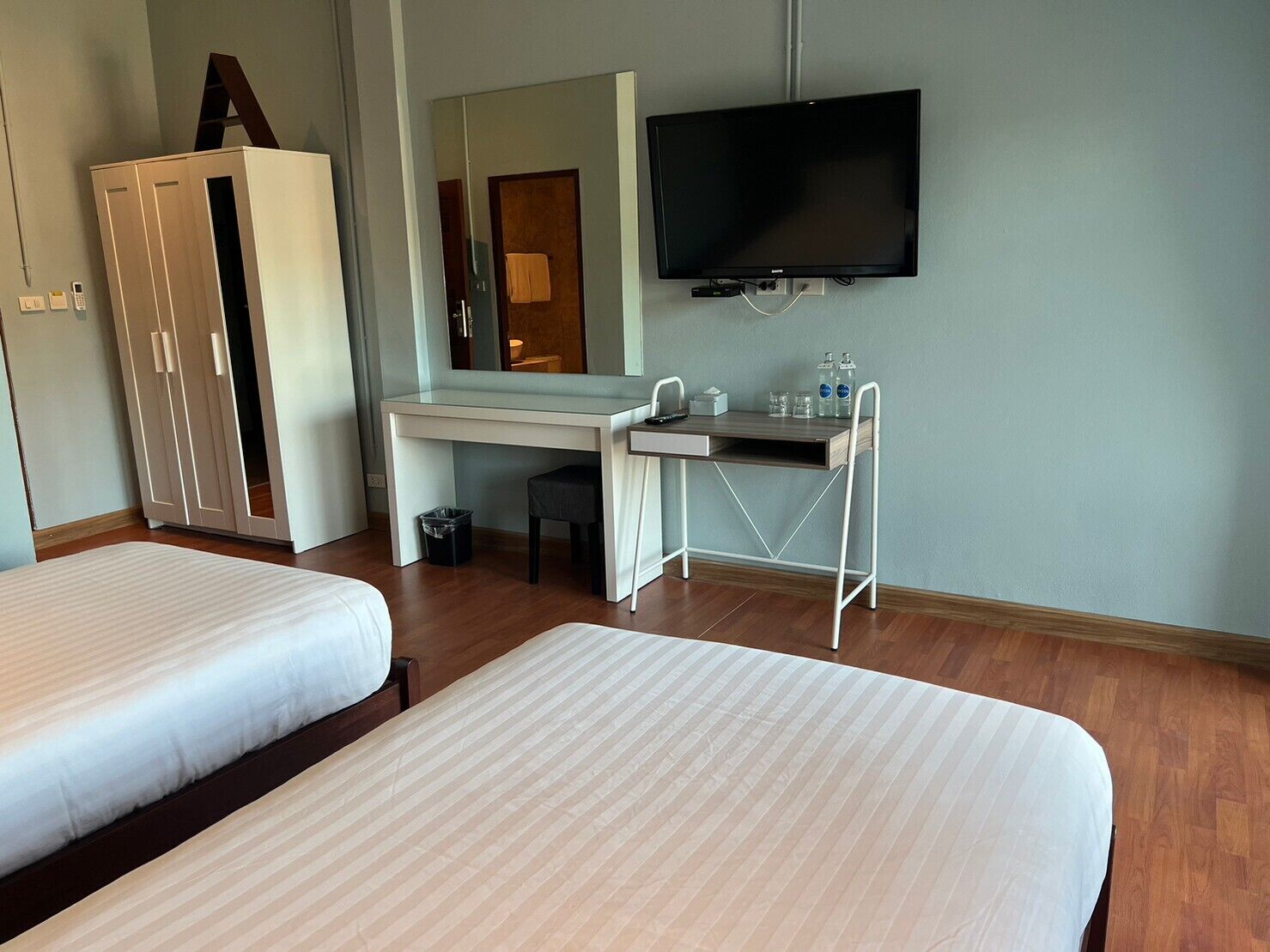 Habitación de hotel con dos camas, un escritorio con silla, televisión y armario.