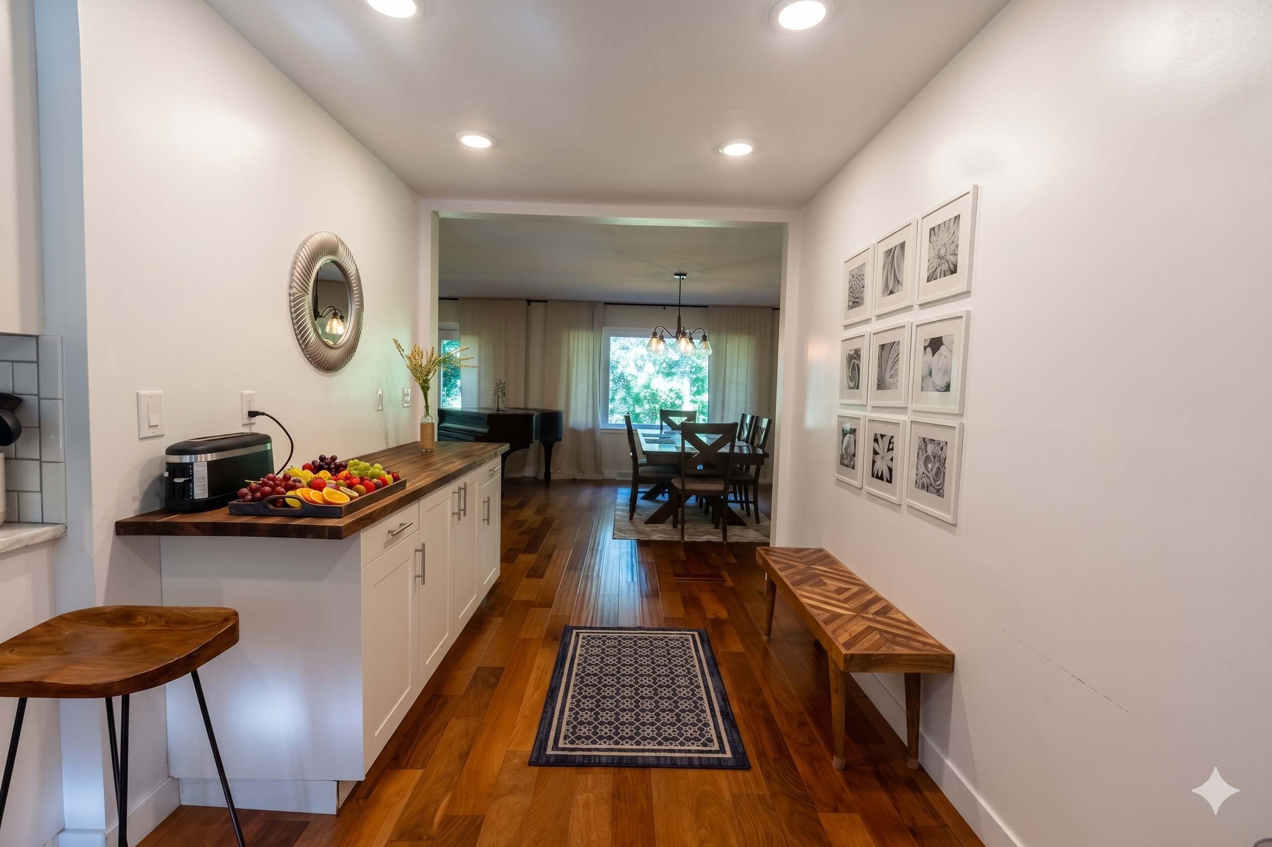 A modern kitchen with a built-in microwave, a fruit bowl, and a dining area with a wooden bench and table.