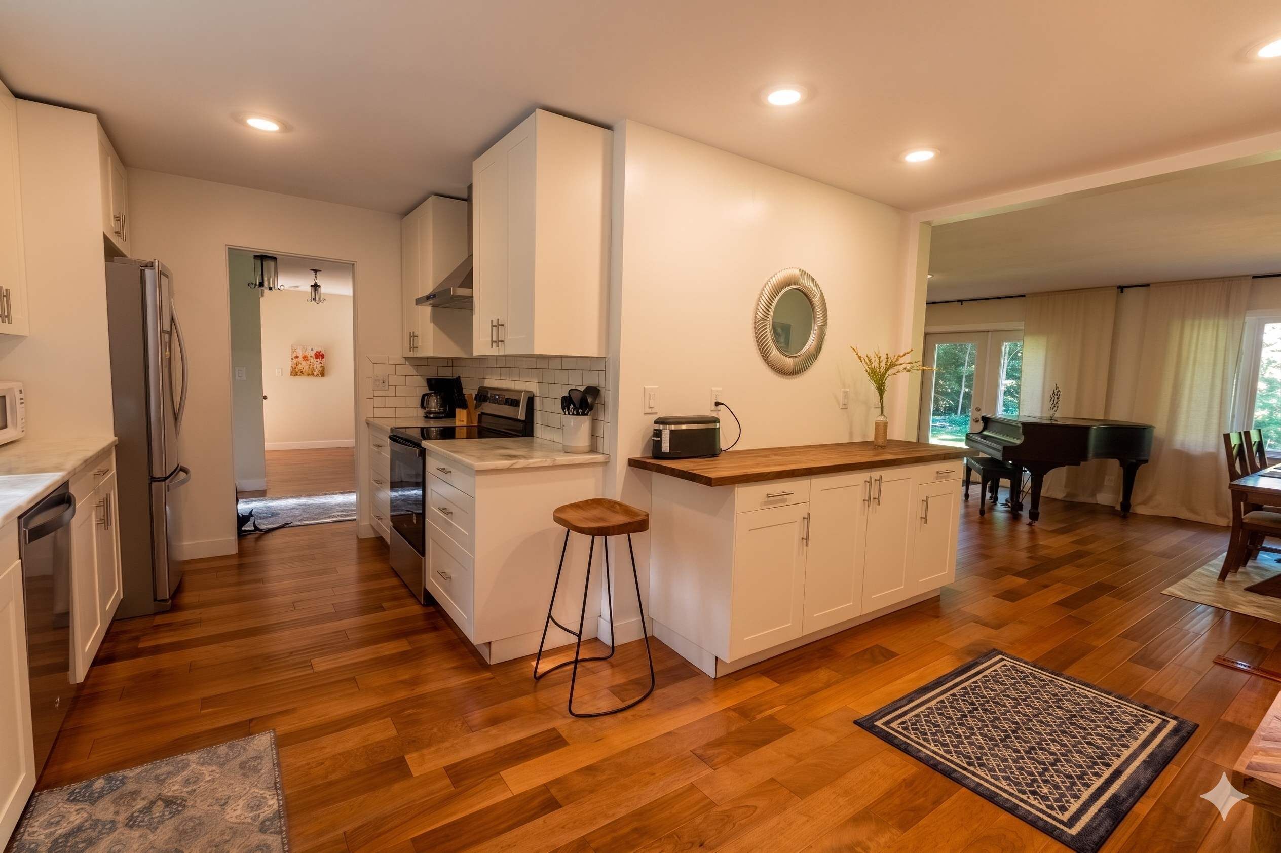 Une cuisine moderne avec un plan de travail en bois, des meubles blancs et un îlot central doté de tabourets.