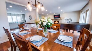 A dining area with a wooden table set for six, surrounded by chairs, with a vase of flowers in the center. - Stunning Ranch in the woods! (Berrien Springs)
