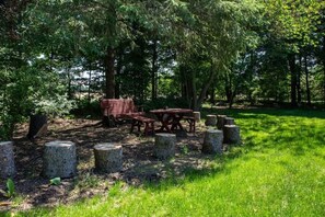 Relax in a serene outdoor setting surrounded by trees and a lush lawn, with a bench and dining table at your disposal.